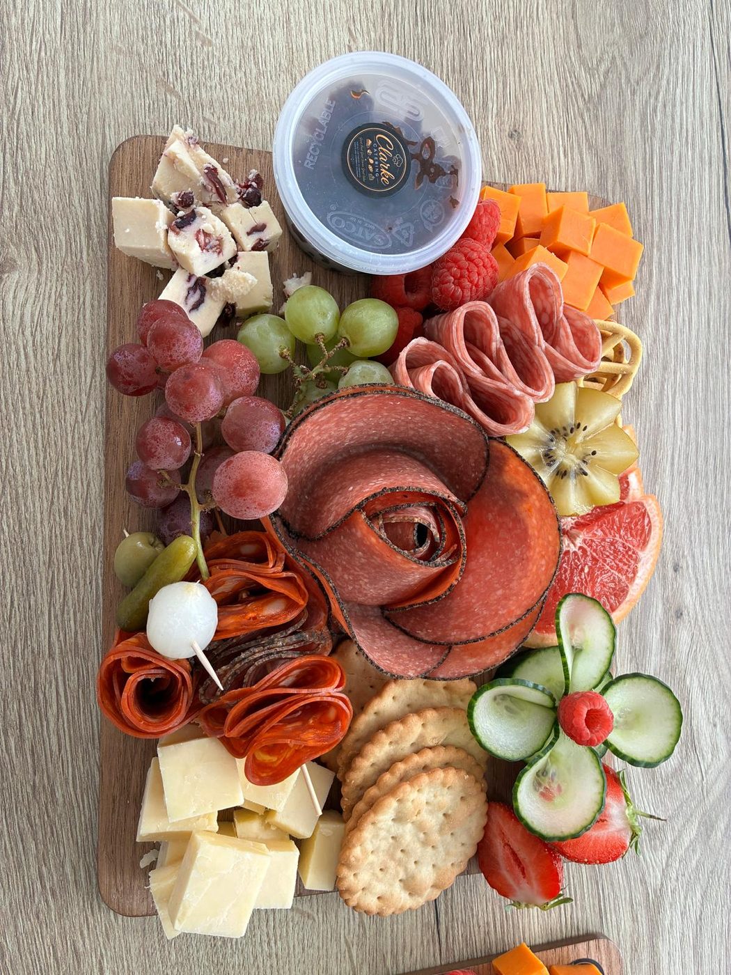 A Clarke Catering grazing board with cheeses, meats, crackers and fresh fruit