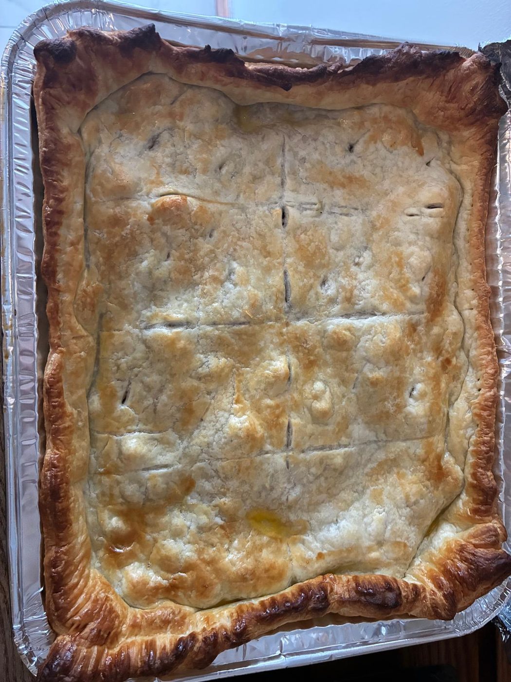 A large homemade pie, freshly baked with a golden puff pastry lid